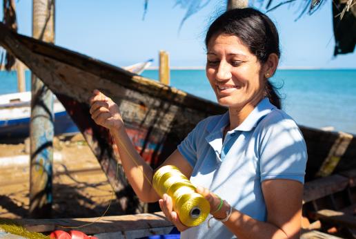 Una mujer trabaja un tejido de pesca.