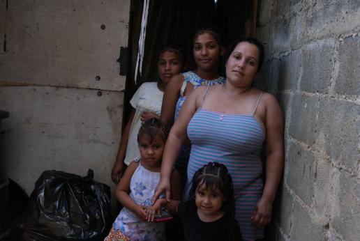 Una mujer con tres de sus hijas miran a cámara.