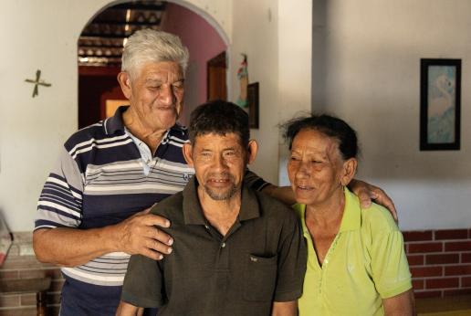 Un señor y una señora parados delante de la cámara con su hijo en el medio.