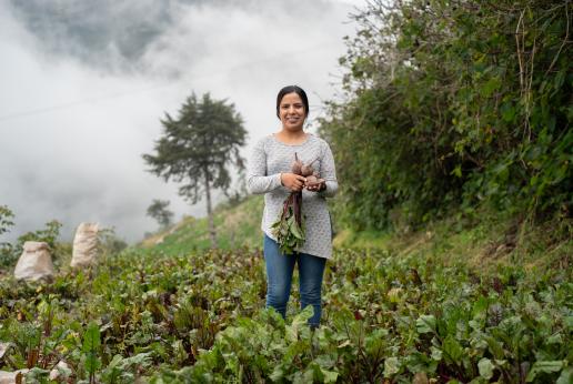 Una mujer sostiene verduras que cultivó. 