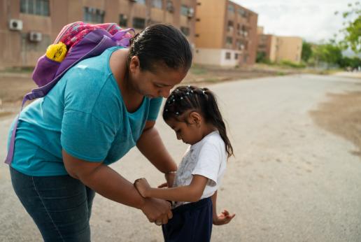 Una madre arregla el uniforme escolar de su hija.