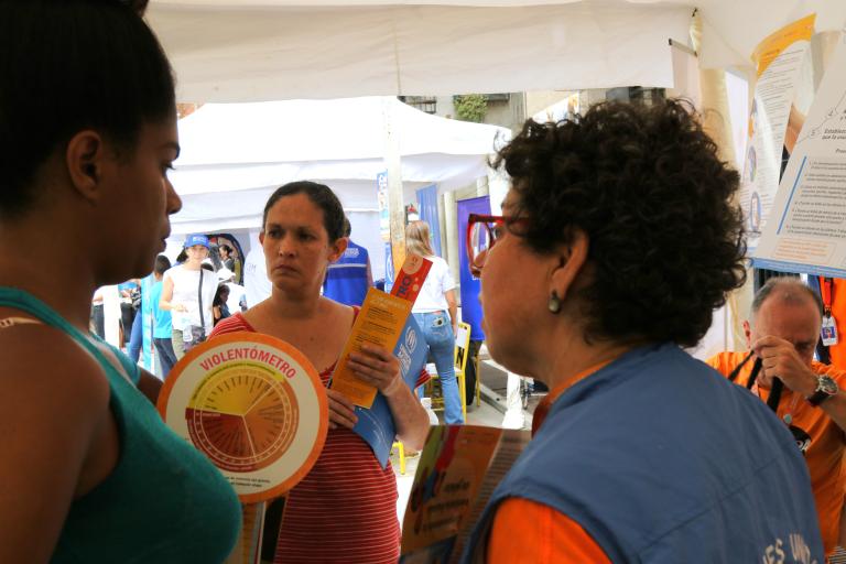 Tres mujeres hablan sosteniendo un violentómetro.