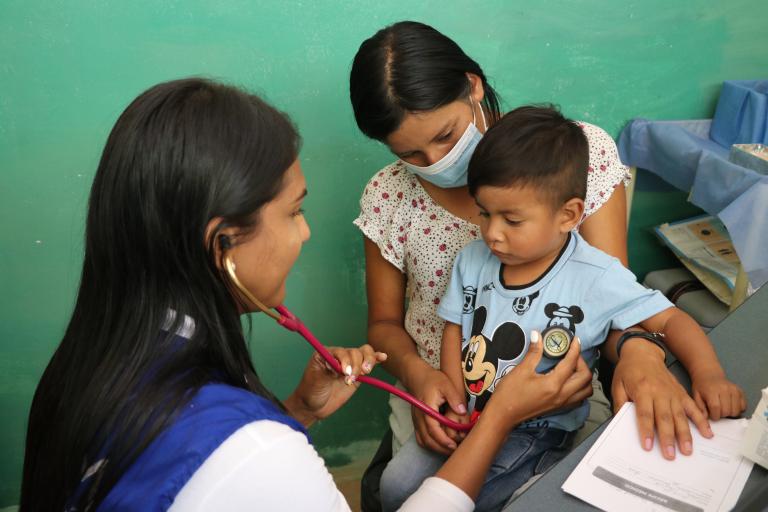  Una mujer y un niño en una consulta médica con una mujer personal de salud.