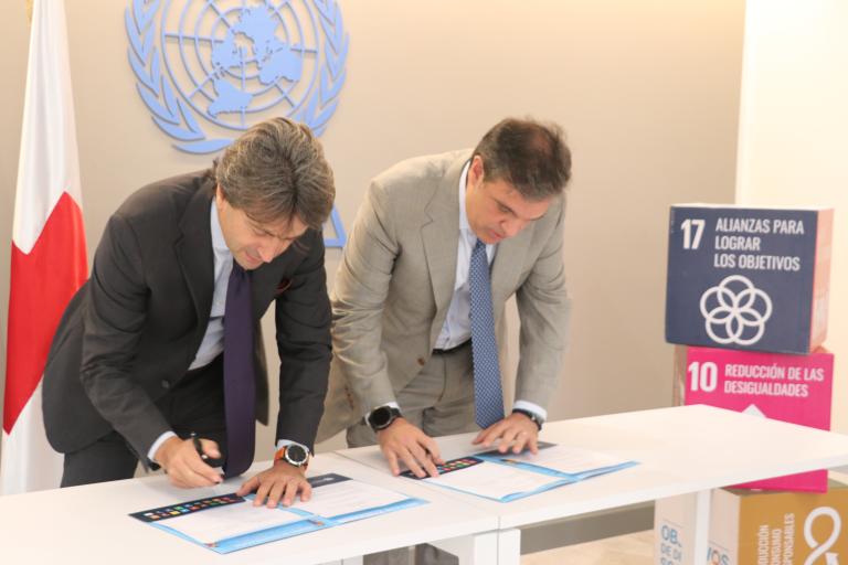 Representantes de Naciones Unidas y la Cruza Roja firman un documento.