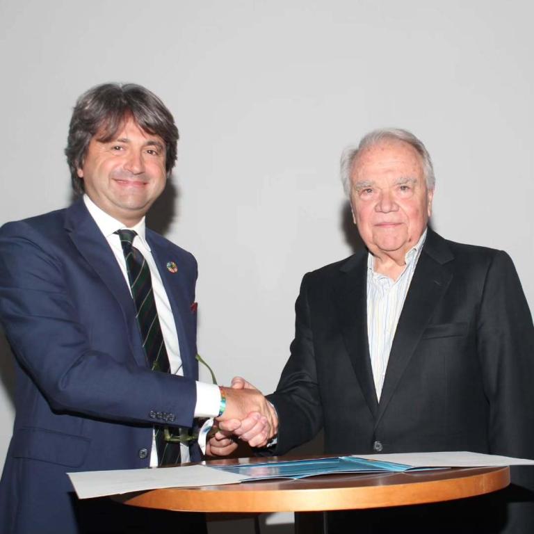 Representante de Naciones Unidas y del IESA se estrechan las manos.